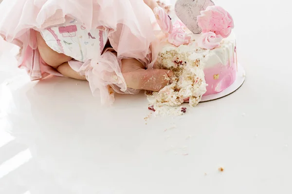 Bater bolo rosa na celebração do primeiro aniversário da menina, bolo de esponja arruinado, marshmallow quebrado, mãos de bebê e atrasos. permissividade, desobediência, comer com as mãos — Fotografia de Stock