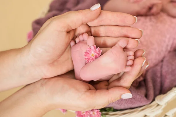 Feet of the newborn baby girl with pink flowers, fingers on the foot, maternal care, love and family hugs, tenderness. — Stock Photo, Image