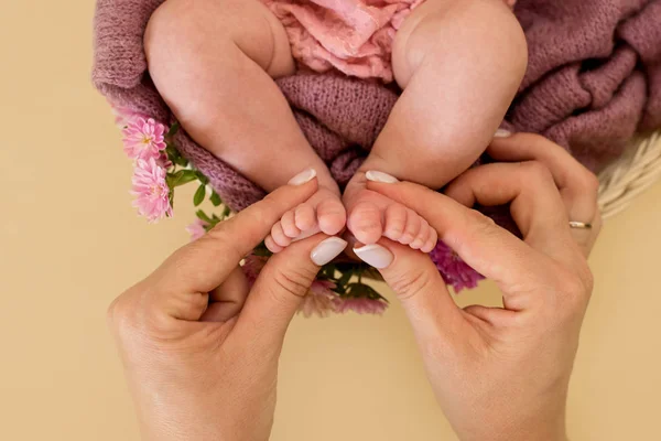 Feet of the newborn baby girl with pink flowers, fingers on the foot, maternal care, love and family hugs, tenderness. — Stock Photo, Image