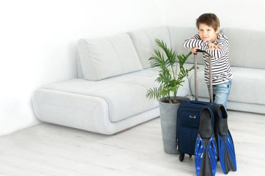 Elinde bavul ve palet olan turist çocuk koronavirüs salgını sırasında evde kalıyor. İzinlerin iptali ve ülkeler arasındaki sınırların kapatılması. Uçuş iptali.