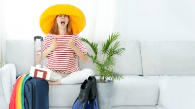 Sarı şapkalı güzel kız evde kalıp tatile çıkmayı planlıyor. Dalış için bavul ve palet. Karantina ve COVID-19 nedeniyle sınırların kapatılması ve uçuşların yasaklanması