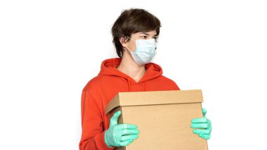 Ulaşılmaz teslimat. Tıbbi maskeli ve eldivenli bir adam bir kutu tutuyor. Ayır, kopyala uzayı. Coronavirus tecrit çevrimiçi ürün ve mal teslimatı, alışveriş