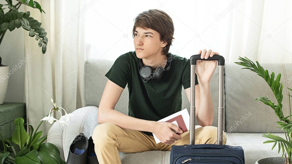 Tourist boy with a suitcase and flippers stays at home during the coronavirus pandemic. Cancellation of leave and closing of borders between countries. Flight cancellation.