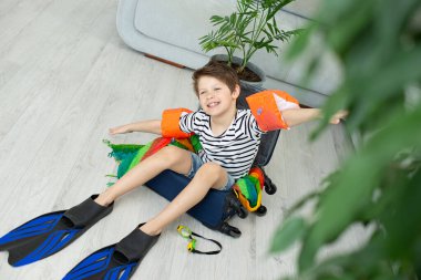 Elinde bavul ve palet olan turist çocuk koronavirüs salgını sırasında evde kalıyor. İzinlerin iptali ve ülkeler arasındaki sınırların kapatılması. Uçuş iptali