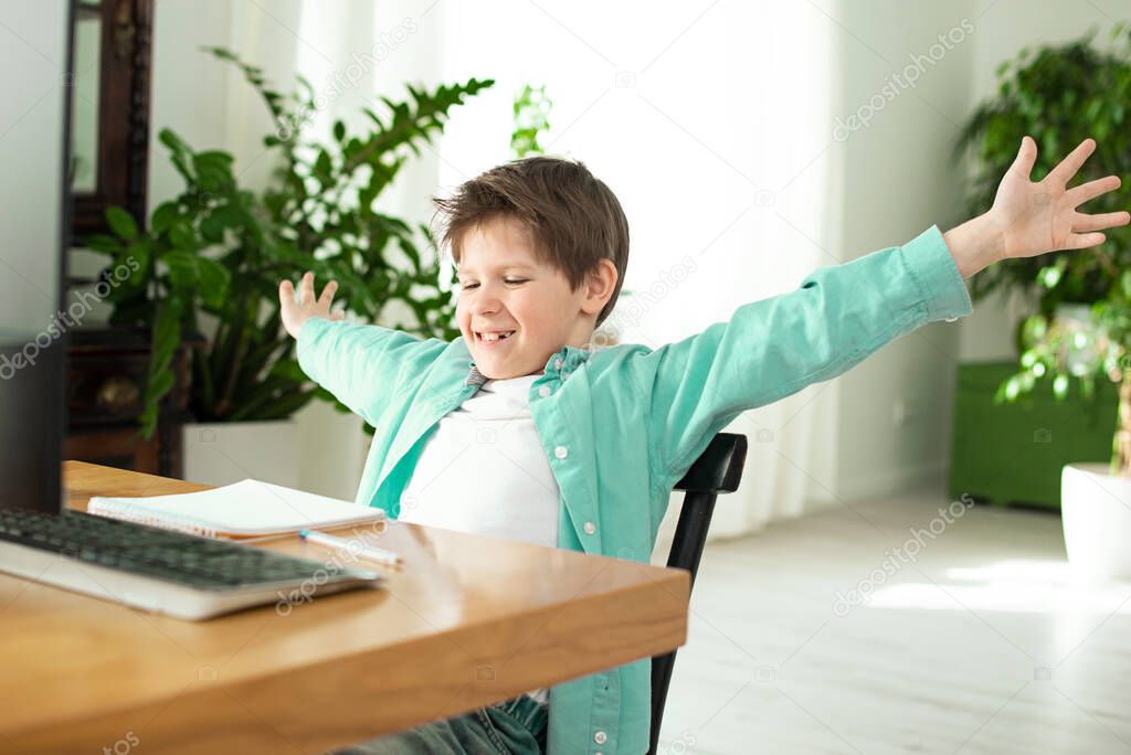 Distance learning in quarantine in coronavirus. Lifestyle. Portrait of successful boy winner with raised hands. Beautiful shouting, isolated. Happy cute child celebrating success with joy