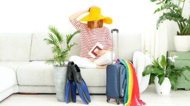 Sarı şapkalı güzel kız evde kalıp tatile çıkmayı planlıyor. Dalış için bavul ve palet. Karantina ve COVID-19 nedeniyle sınırların kapatılması ve uçuşların yasaklanması