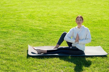 Bir kadın çimlerin üzerinde yoga yapıyor. Bental sağlık, anksiyete azaltma, iç huzur