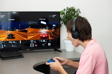 Orenburg, Rusya, 19 Haziran 2020. Büyük gerçekçilik sporu. Ergen, kulaklık, joystick ve oyun konsoluyla bilgisayar oyunu oynuyor..