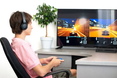 Genç çocuk internet üzerinden kulaklık, joystick ve oyun konsoluyla bilgisayar oyunu oynuyor..