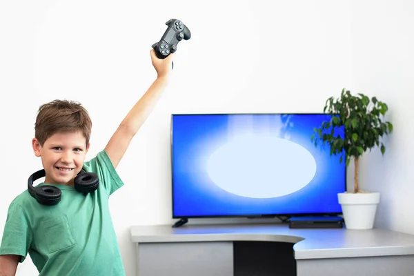 Boy juega un juego de ordenador con auriculares y un joystick, consola de juegos . —  Fotos de Stock