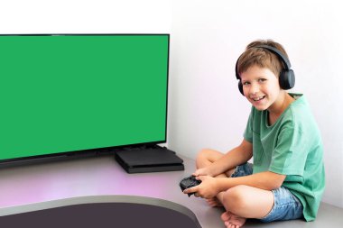 Genç çocuk internet üzerinden kulaklık, joystick ve oyun konsoluyla bilgisayar oyunu oynuyor..