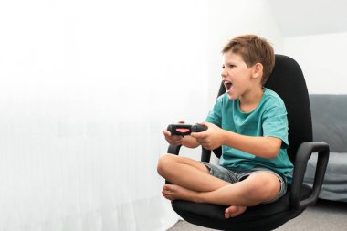 Genç çocuk internet üzerinden kulaklık, joystick ve oyun konsoluyla bilgisayar oyunu oynuyor..