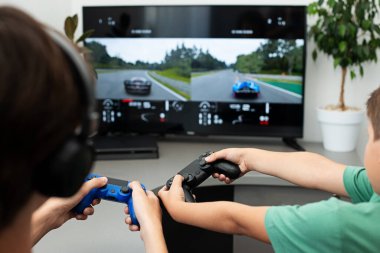 Genç çocuk internet üzerinden kulaklık, joystick ve oyun konsoluyla bilgisayar oyunu oynuyor..