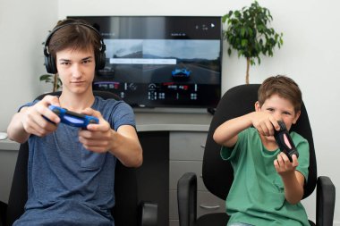 Genç çocuk internet üzerinden kulaklık, joystick ve oyun konsoluyla bilgisayar oyunu oynuyor..