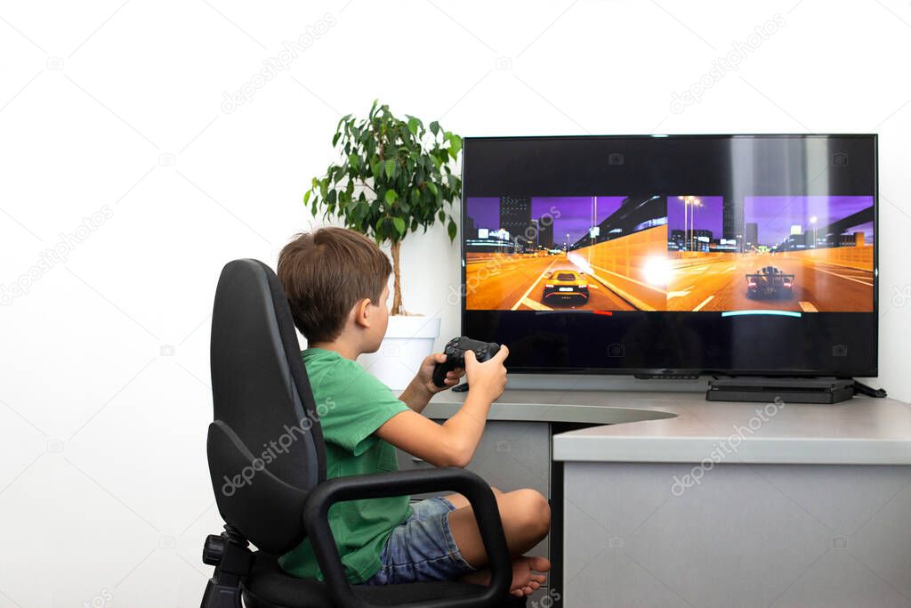 Teenager boy online plays a computer game with headphones and a joystick, game console.