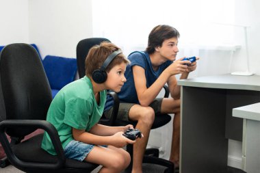 Genç çocuk internet üzerinden kulaklık, joystick ve oyun konsoluyla bilgisayar oyunu oynuyor..