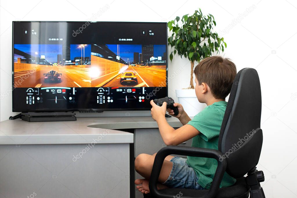 Teenager boy online plays a computer game with headphones and a joystick, game console.