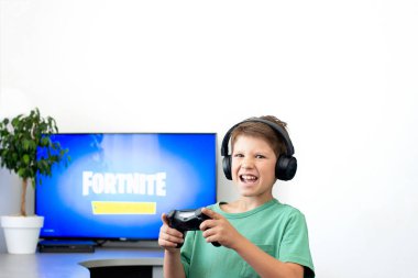 Ergen, kulaklık, joystick ve oyun konsoluyla bilgisayar oyunu oynuyor..