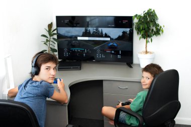 Genç çocuk internet üzerinden kulaklık, joystick ve oyun konsoluyla bilgisayar oyunu oynuyor..