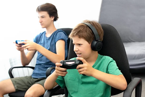Genç çocuk internet üzerinden kulaklık, joystick ve oyun konsoluyla bilgisayar oyunu oynuyor..