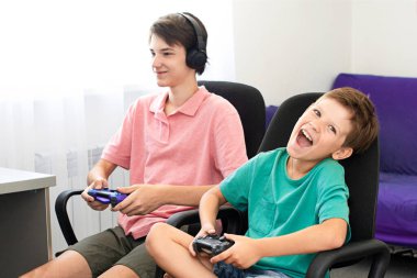 Genç çocuk internet üzerinden kulaklık, joystick ve oyun konsoluyla bilgisayar oyunu oynuyor..