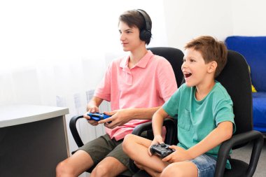 Genç çocuk internet üzerinden kulaklık, joystick ve oyun konsoluyla bilgisayar oyunu oynuyor..