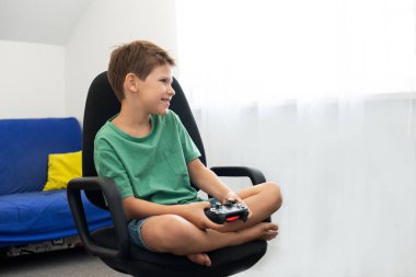 Genç çocuk internet üzerinden kulaklık, joystick ve oyun konsoluyla bilgisayar oyunu oynuyor..
