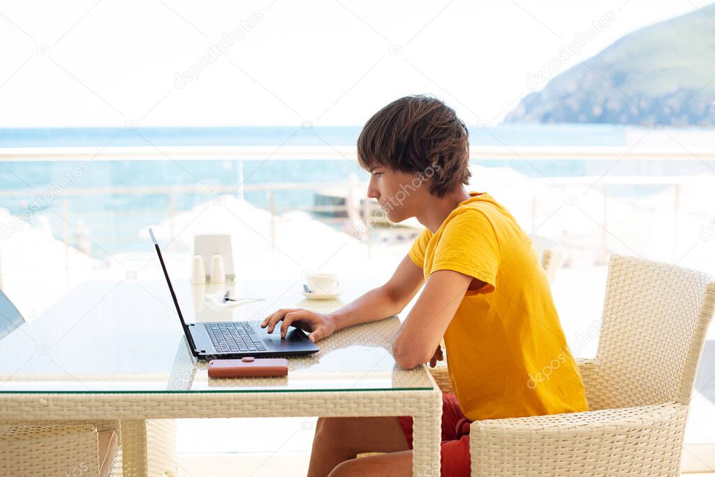 Workplace in a cafe with a sea view. Man working on a laptop in a cafe. Copy space, Mock up.