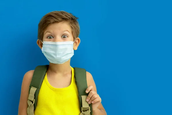 Skolpojke i medicinsk mask med ryggsäck. Tillbaka till skolan. Kopiera utrymme — Stockfoto
