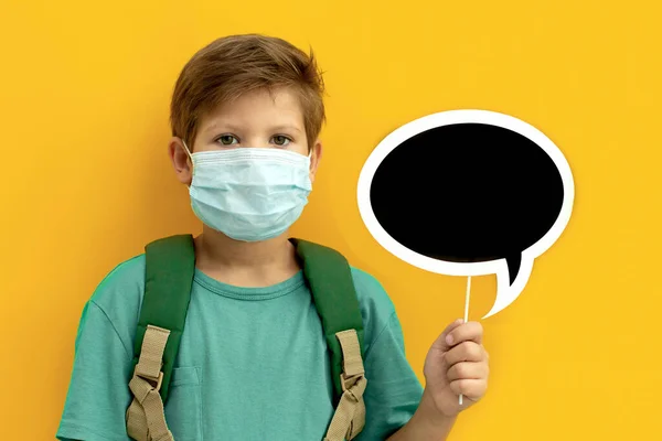 Studente con una maschera medica con uno zaino. Torniamo a scuola. Copia spazio — Foto Stock