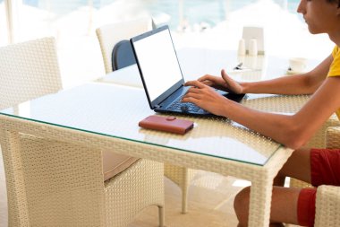 Deniz manzaralı bir kafede iş yeri. Kafede dizüstü bilgisayarda çalışan bir adam. Uzayı kopyala Model.