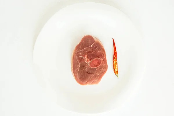 pieces of raw turkey meat, chopped leg steak, portioned barbecue pieces, on white background with a sprig of rosemary and red hot pepper. isolate