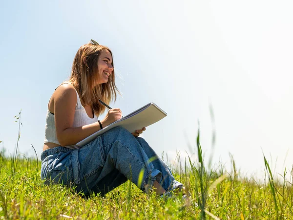 A Caucasian female sitting and drawing in nature
