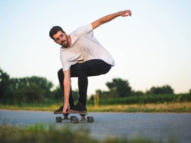 Açık havada kaykay süren yakışıklı beyaz bir erkeğin yüzeysel odak noktası.