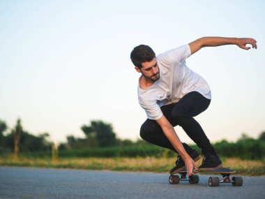 Açık havada kaykay süren yakışıklı beyaz bir erkeğin yüzeysel odak noktası.