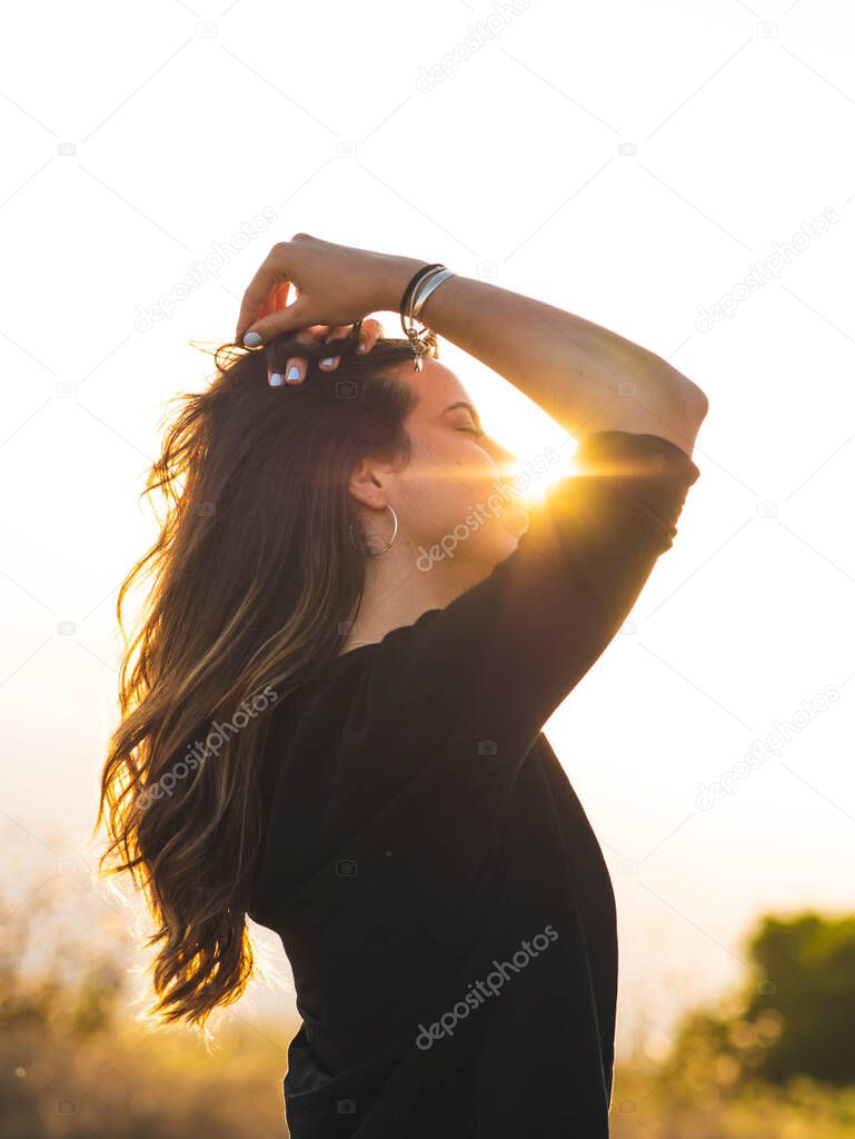 A vertical shot of a young Caucasian woman during the sunset