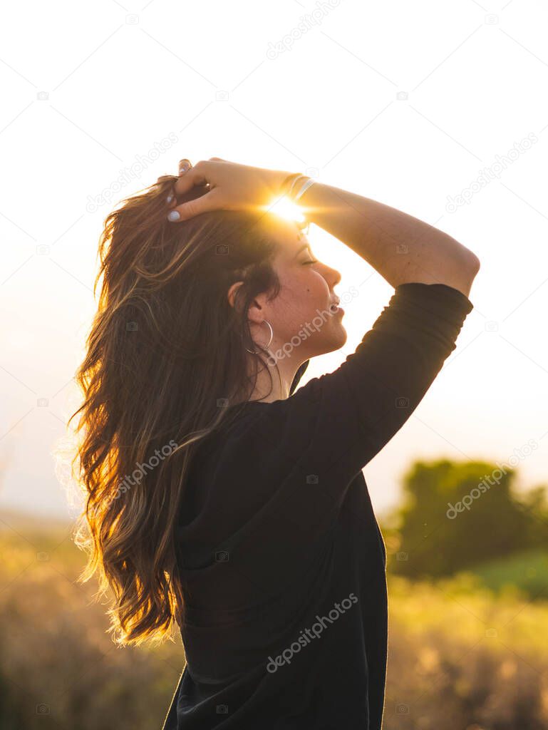 A vertical shot of a young Caucasian woman during the sunset