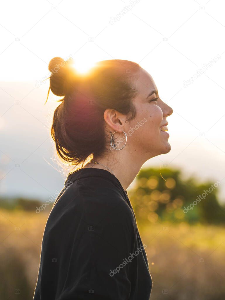 A vertical shot of a young Caucasian woman during the sunset