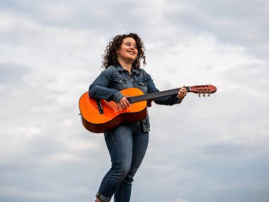 Buğday tarlasında gitar çalan genç ve güzel bir kadının sığ odak noktası.