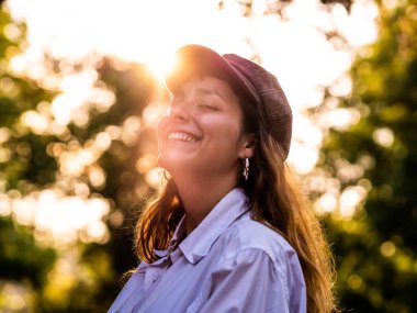 Beyaz gömlekli, harika bir gülümsemesi olan esmer bir kadının dikey resmi.