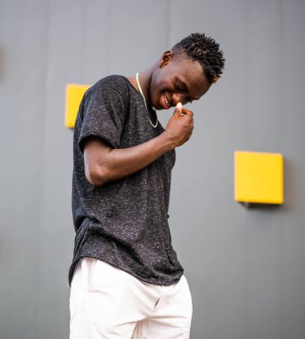 Gri duvar arkasında genç siyah bir erkeğin portresi.