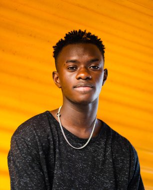 Sarı arka planda genç siyah bir erkeğin sığ odak noktası.