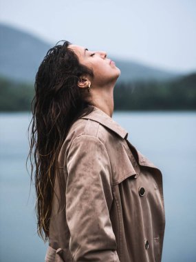 Genç bir kadın yaya köprüsünde tek başına duruyor ve göle bakıyor. Suyun üzerinde sis. Sisli hava. Soğuk bir sabah. Arka plan.