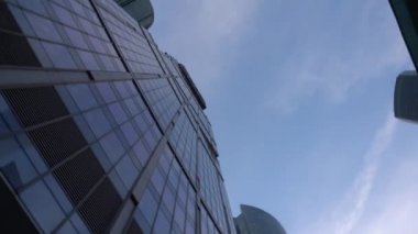 Cam yapılmış olağandışı şeklin modern mavi gökdelenler. Aşağıdan döndürme