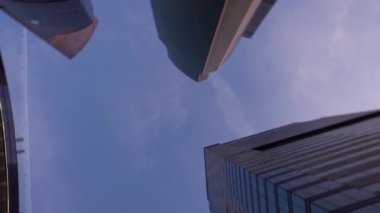 Cam yapılmış olağandışı şeklin modern gökdelenler. Döndürme ile aşağıdan yukarı görünüm