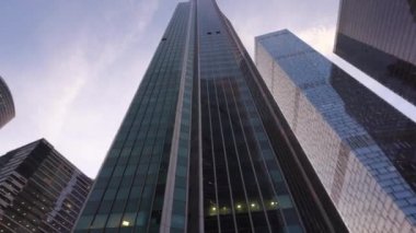 Cam yapılmış olağandışı şeklin modern gökdelenler. Döndürme ile aşağıdan yukarı görünüm