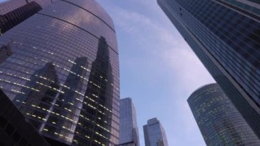 Modern, camdan yapılmış gökdelenler önünde dönen kamera düşük açı çekim