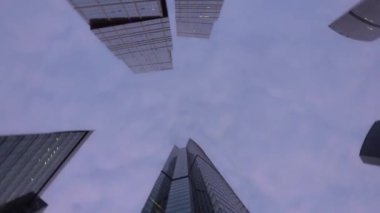 Cam yapılmış olağandışı şeklin modern gökdelenler. Döndürme ile aşağıdan yukarı görünüm