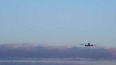 Uçak iniyor. İçinde iki daha fazla uçak, mavi gökyüzü mor turuncu bulutlar arka plan