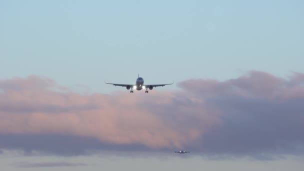 Dois aviões estão voando no céu. No fundo céu azul, roxo nuvens laranja — Vídeo de Stock